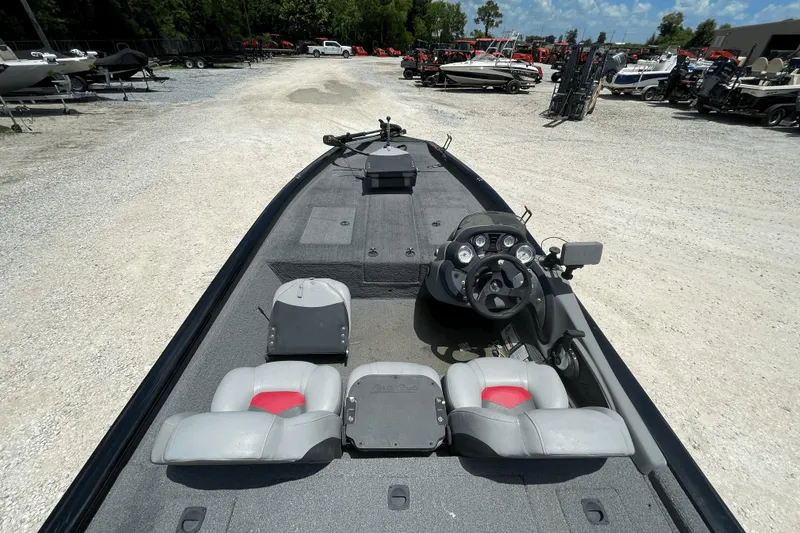 Slide: The Image of 2016 Tracker Pro Team 190 TX boat interior with steering console and seating in a boatyard. - 2