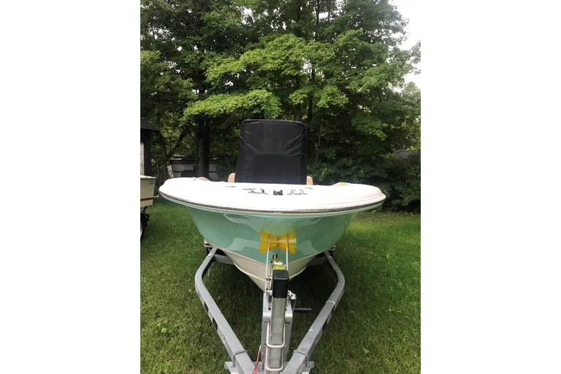 Slide: The Image of 2026 Pioneer 180 Islander boat on trailer, parked on grass with trees in background. - 8