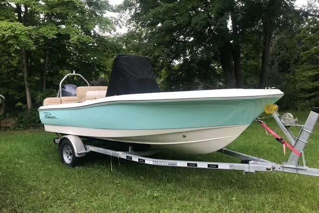 Slide: The Image of 2026 Pioneer 180 Islander boat on trailer, parked on grass with trees in background. - 9