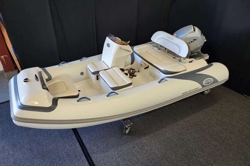 Slide: The Image of 2026 Walker Bay Generation 12 LTE inflatable boat with seating and motor, displayed indoors. - 3