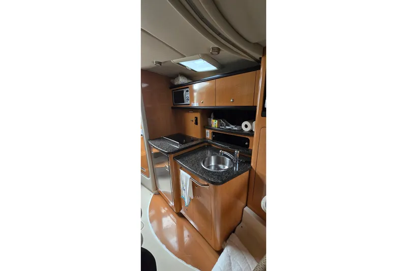 Slide: The Image of 2006 Chaparral Signature 310 yacht interior with kitchenette, featuring wood cabinets and stainless steel sink. - 16