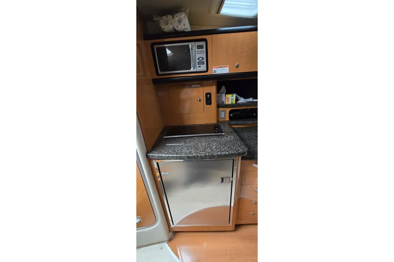 Slide: The Image of 2006 Chaparral Signature 310 yacht kitchen with microwave, stove, and compact fridge. - 19