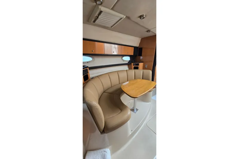 Slide: The Image of Interior of 2006 Chaparral Signature 310 boat with curved seating and wooden table. - 21