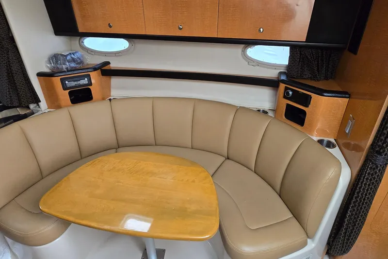 Slide: The Image of Interior of 2006 Chaparral Signature 310 yacht with beige seating and wooden table. - 22