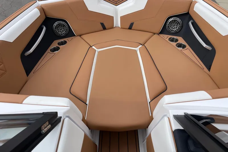 Slide: The Image of 2026 Nautique Super Air Nautique GS24 boat interior with tan upholstery and cup holders. - 11