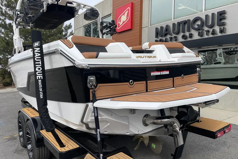 Slide: The Image of 2026 Nautique Super Air Nautique GS24 boat at dealership, rear view with teak deck. - 3