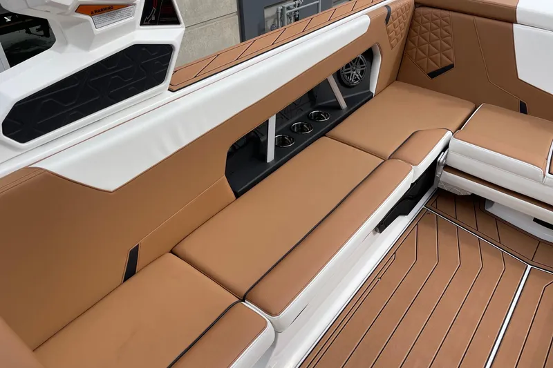 Slide: The Image of 2026 Nautique Super Air Nautique GS24 interior with tan seating and cup holders. - 7