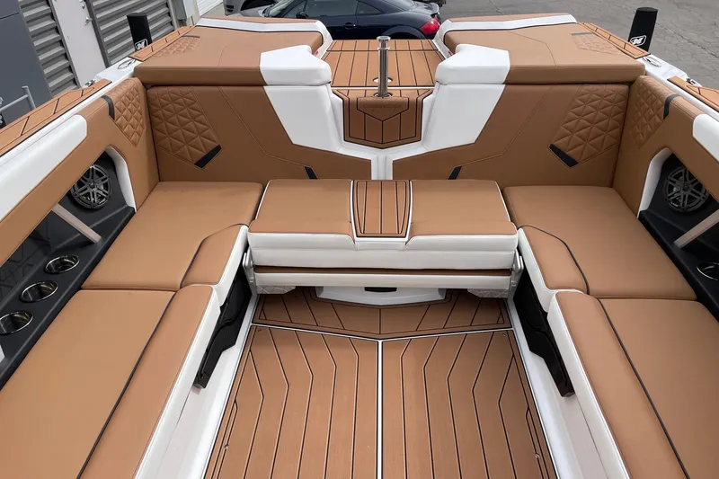 Slide: The Image of 2026 Nautique Super Air Nautique GS24 interior with tan and white seating, cup holders, and speakers. - 8