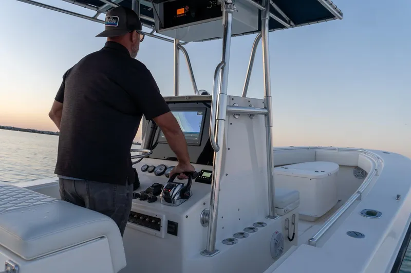 Slide: The Image of Man steering 2005 Contender 27 Tournament boat at sunset on calm waters. - 13