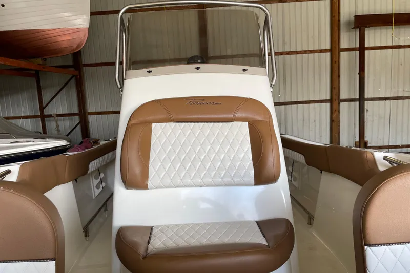 Slide: The Image of 2026 Pioneer 202 Islander boat interior with brown and white seating in a storage facility. - 13