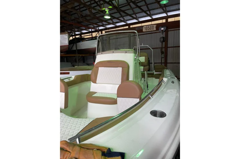 Slide: The Image of 2026 Pioneer 202 Islander boat with tan and white seating in a storage facility. - 18