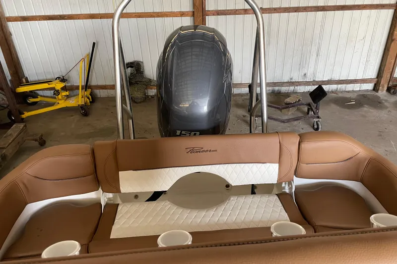 Slide: The Image of 2026 Pioneer 202 Islander boat interior with brown seating and outboard motor in a garage. - 19