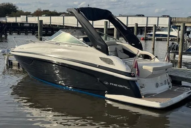 The Image of 2023 Regal 28 Express boat docked in marina, sleek design, black and white exterior. - 1