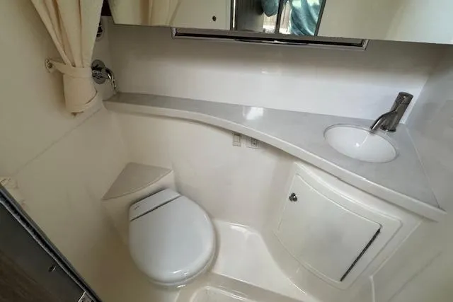 Slide: The Image of 2023 Regal 28 Express boat bathroom with modern sink, toilet, and storage cabinet. - 26