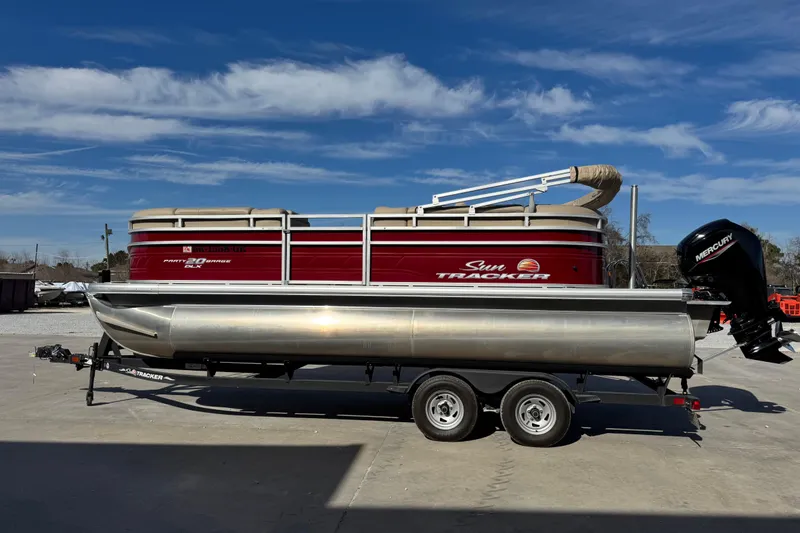 The Image of 2024 Sun Tracker Party Barge 20 DLX pontoon boat on trailer, under clear blue sky. - 0