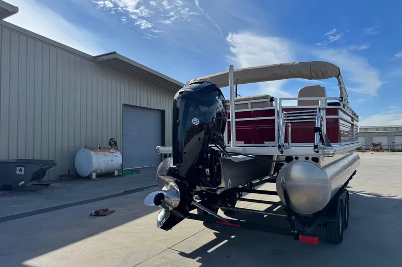 Slide: The Image of 2024 Sun Tracker Party Barge 20 DLX pontoon boat with outboard motor in industrial setting. - 3