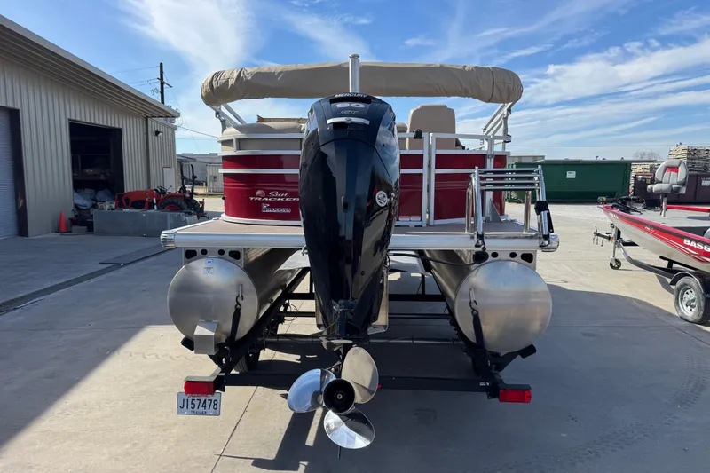 Slide: The Image of 2024 Sun Tracker Party Barge 20 DLX pontoon boat with outboard motor, parked outdoors. - 4
