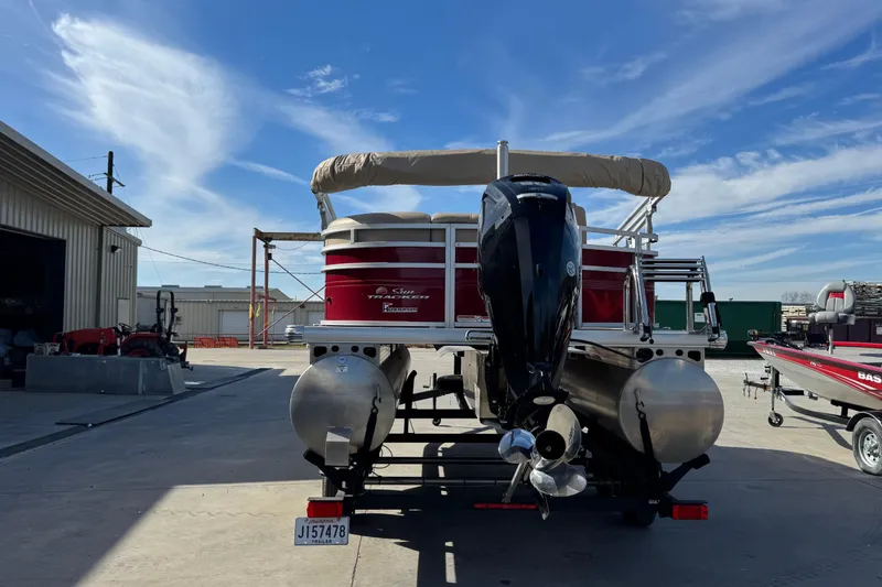 Slide: The Image of 2024 Sun Tracker Party Barge 20 DLX pontoon boat with outboard motor, parked outdoors. - 5