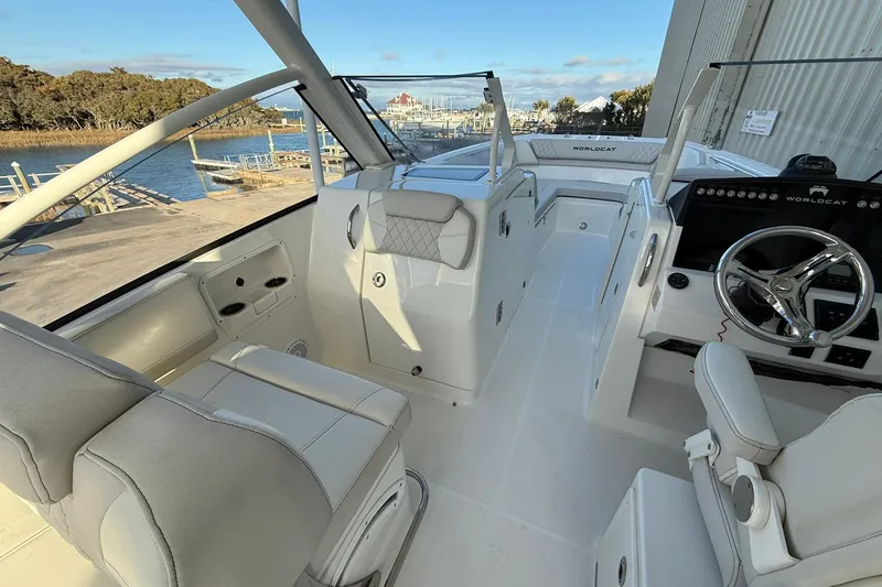 Slide: The Image of 2024 World Cat 280 DC-X boat interior with modern seating and steering wheel, dockside view. - 10