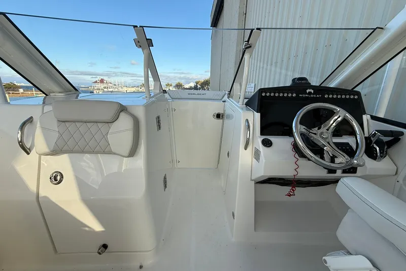 Slide: The Image of 2024 World Cat 280 DC-X boat interior with steering wheel and seating, dockside view. - 18