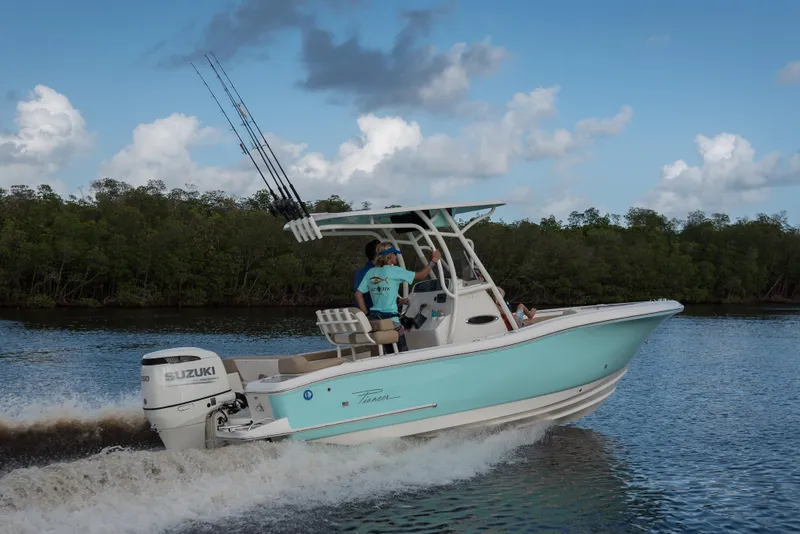 Slide: The Image of 2026 Pioneer 222 Islander boat cruising on water with Suzuki engine, under blue sky. - 2