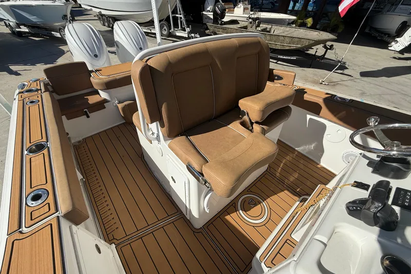 Slide: The Image of 2024 Sea Hunt Gamefish 27 boat interior with tan seating and wood-style flooring. - 11