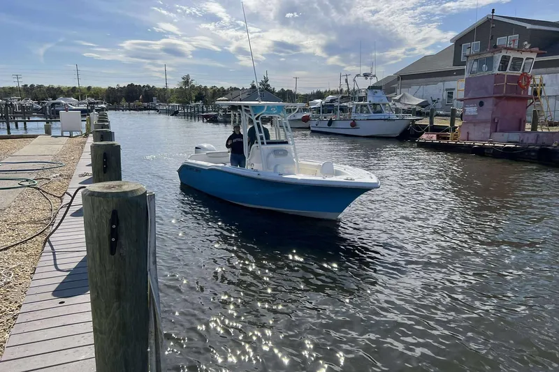 Slide: The Image of 2022 Key West 239 FS boat navigating a marina with docks and buildings in the background. - 2