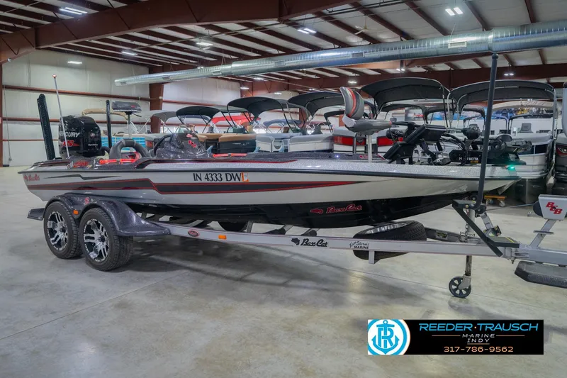 Slide: The Image of 2016 Bass Cat Cougar boat in showroom, featuring sleek design and dual-axle trailer. - 5