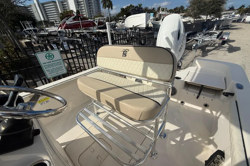 Slide: The Image of 2023 Carolina Skiff 21 LS boat with beige seating and chrome details in a marina setting. - 7