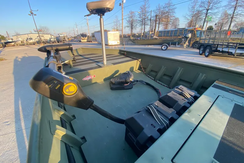 Slide: The Image of 2012 Alumacraft 1448 Jon boat with trolling motor and battery, parked outdoors. - 14