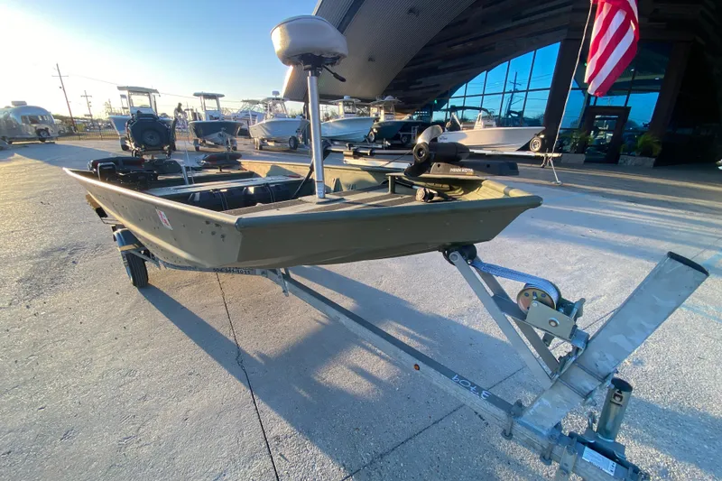 Slide: The Image of 2012 Alumacraft 1448 Jon boat on trailer, displayed outdoors with American flag. - 8