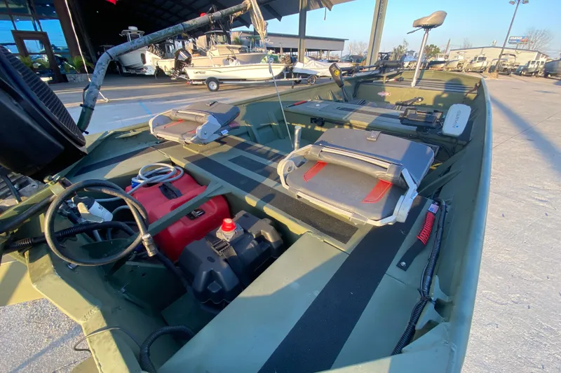 Slide: The Image of 2012 Alumacraft 1448 Jon boat interior with seats and equipment, parked outdoors. - 9