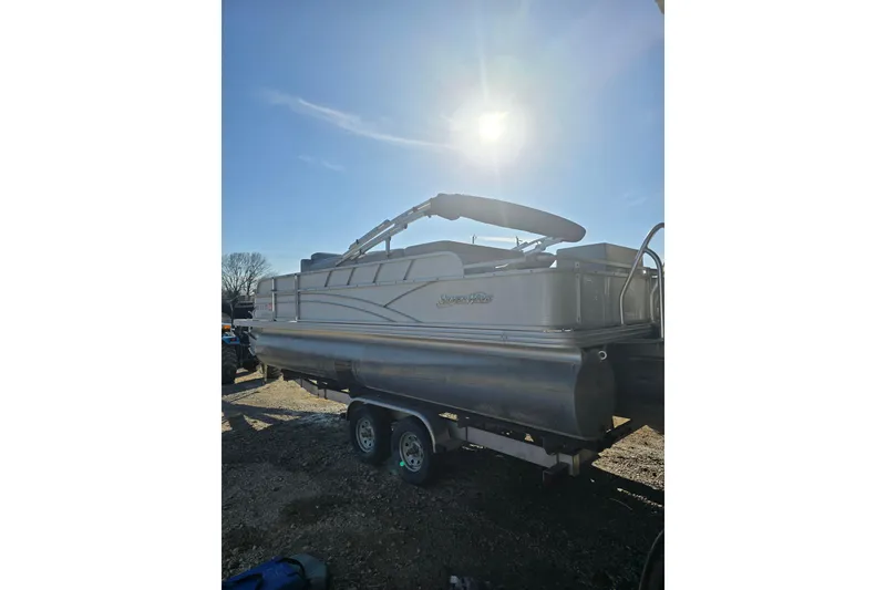 Slide: The Image of 2017 SilverWave 230 Island pontoon boat on trailer under bright sun. - 15