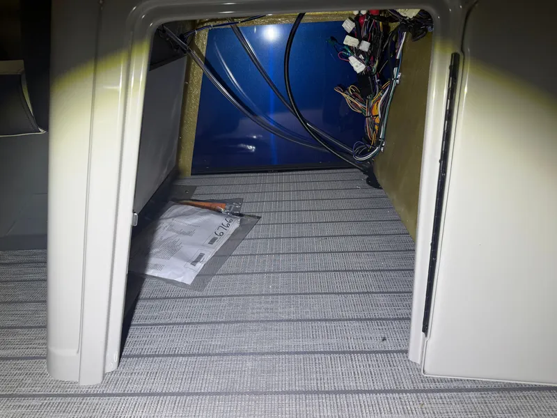 Slide: The Image of A view inside a storage compartment with wires and an envelope on the floor. - 25