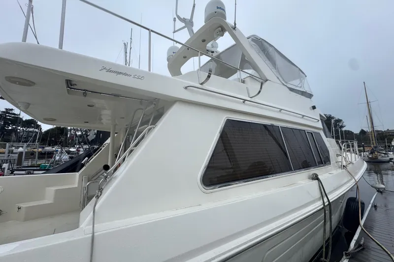 Slide: The Image of Luxury 2002 Hampton 550 yacht docked at marina, showcasing sleek design and spacious deck. - 10