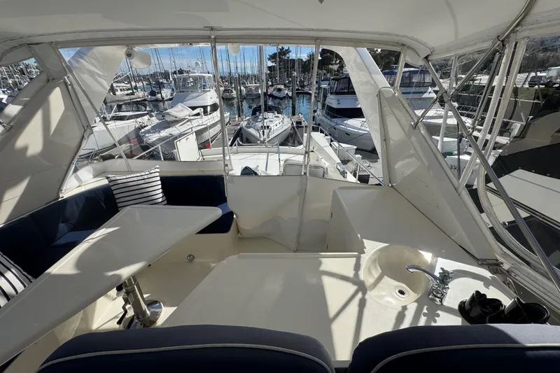 Slide: The Image of Interior view of a 2002 Hampton 550 yacht, featuring seating and marina backdrop. - 15