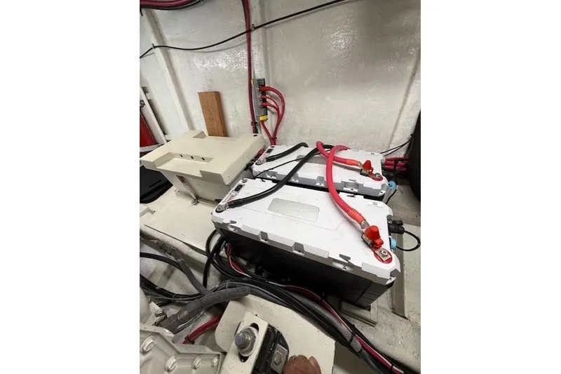 Slide: The Image of Battery setup in a 2002 Hampton 550 yacht engine room with red and black cables. - 49
