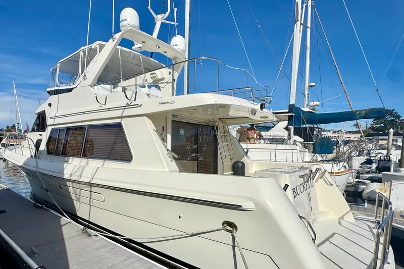 Slide: The Image of 2002 Hampton 550 yacht docked at marina under clear blue sky. - 5