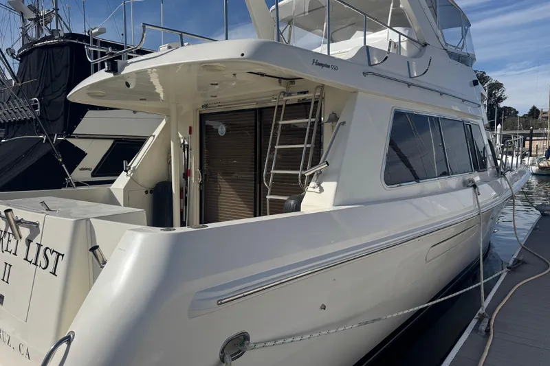 Slide: The Image of 2002 Hampton 550 yacht docked at marina, featuring sleek design and spacious deck. - 6