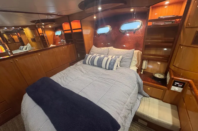 Slide: The Image of Luxurious 2002 Hampton 550 yacht bedroom with cozy bedding and elegant wood paneling. - 73