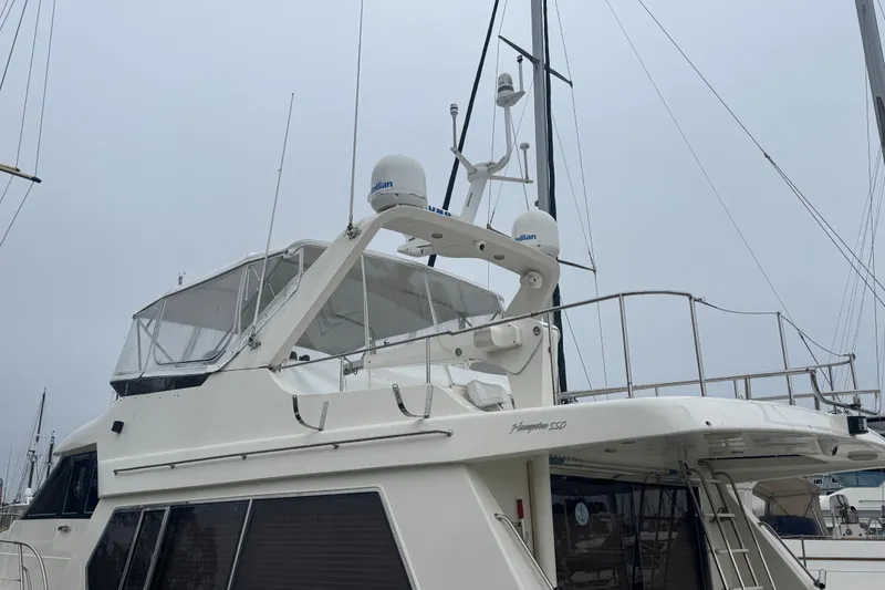 Slide: The Image of 2002 Hampton 550 yacht docked, featuring radar equipment and spacious upper deck. - 9
