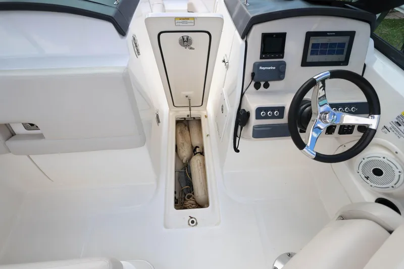 Slide: The Image of 2019 Boston Whaler 230 Vantage cockpit with steering wheel and storage compartment. - 28