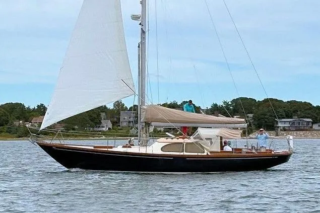 Slide: The Image of 1967 Columbia Constellation sailboat on water, with sails up, near shoreline houses. - 23