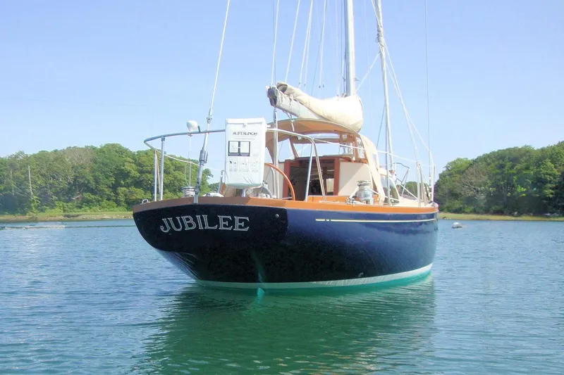 Slide: The Image of 1967 Columbia Constellation sailboat "Jubilee" on calm water, surrounded by lush greenery. - 3