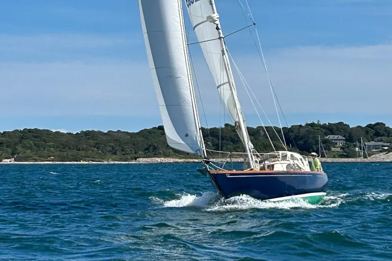 Slide: The Image of 1967 Columbia Constellation sailboat navigating blue waters near a wooded shoreline. - 32