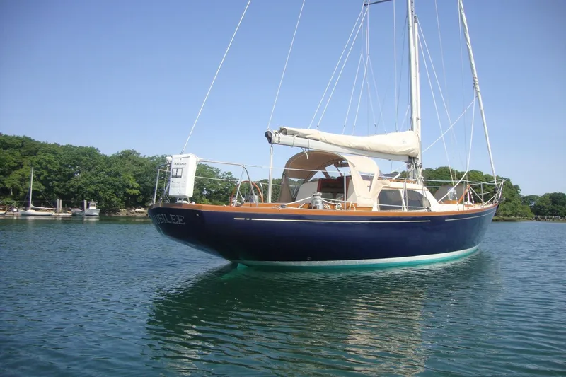Slide: The Image of 1967 Columbia Constellation sailboat on calm water, surrounded by lush greenery. - 4