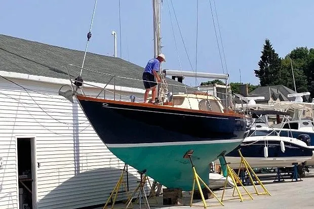 Slide: The Image of 1967 Columbia Constellation sailboat on stands, with person performing maintenance. - 50