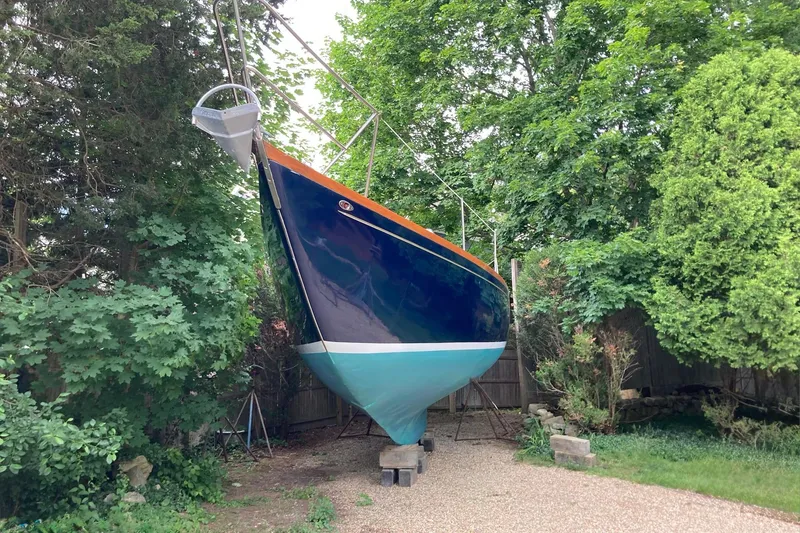 Slide: The Image of 1967 Columbia Constellation sailboat on land, surrounded by lush green trees. - 54