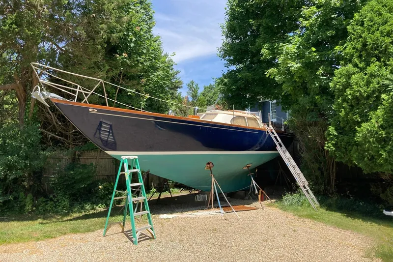 Slide: The Image of 1967 Columbia Constellation sailboat on land, surrounded by trees, with ladders for maintenance. - 55
