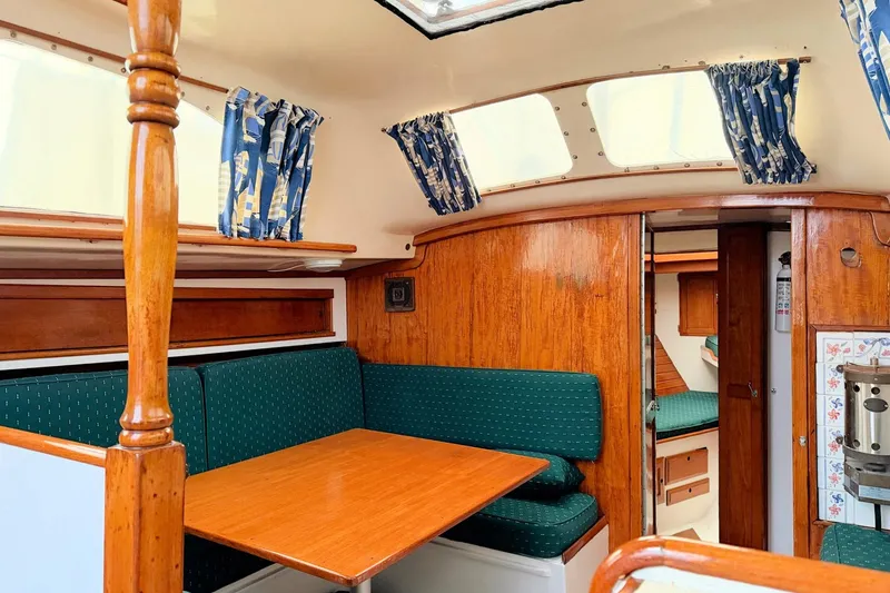 Slide: The Image of 1967 Columbia Constellation yacht interior with wooden finish, green seating, and nautical curtains. - 84